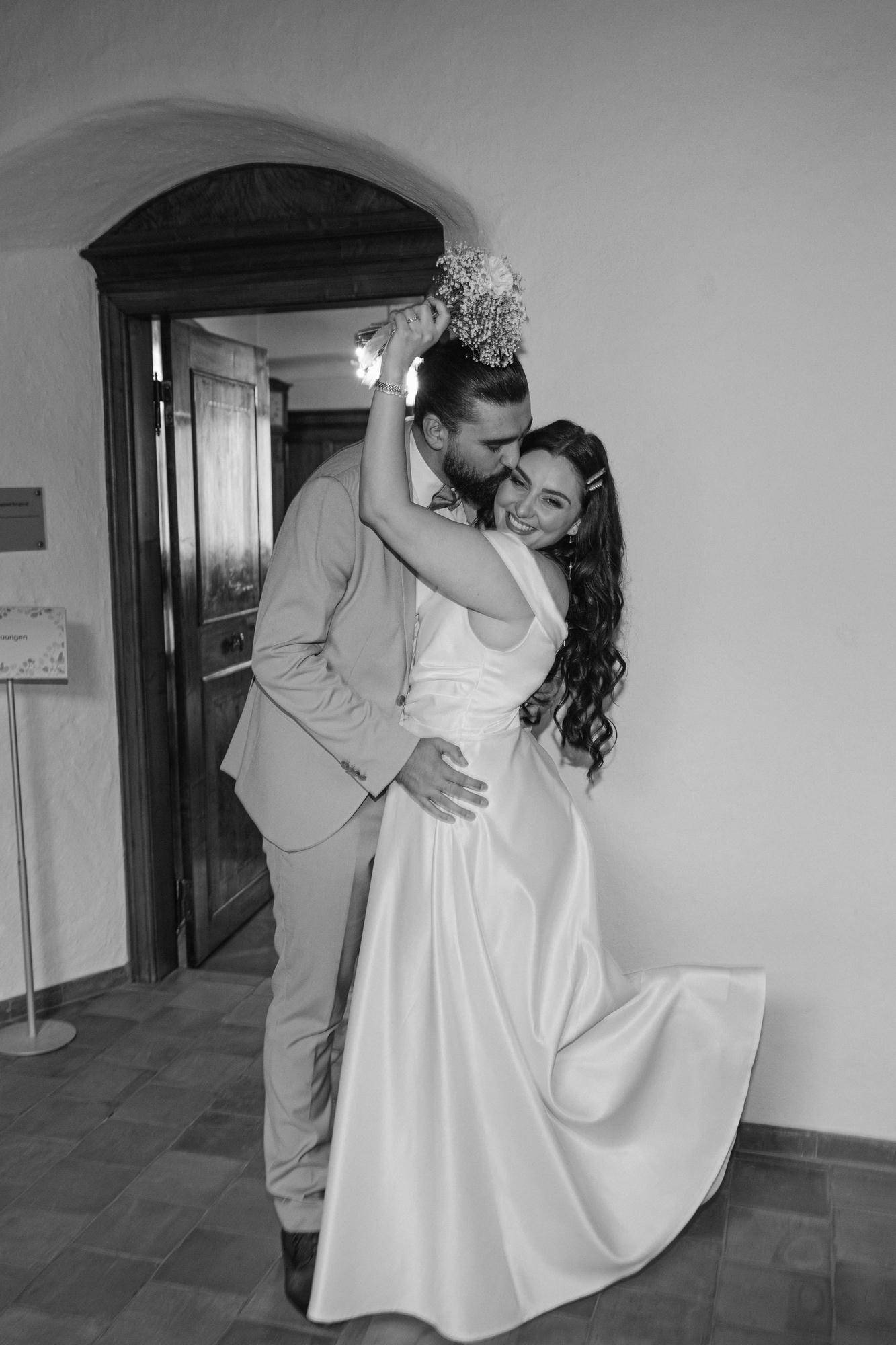 Verliebt tanzendes Brautpaar in einem eleganten Hochzeitsoutfit